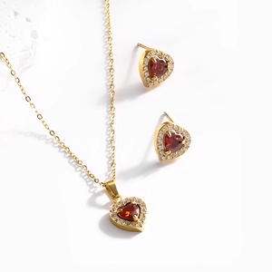 Élégante parure de bijoux cœur dorés avec pierres rouges et détails en zircon