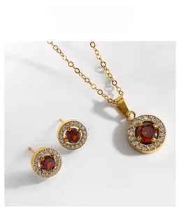 Détail d'un ensemble de bijoux en acier titane doré avec pierres rouges et zircons