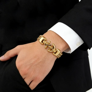 Close-up of men's gold anchor bracelet with double-row chain on model wrist