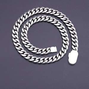 Polished stainless steel Cuban link chain necklace with flat clasp on grey background