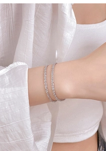 Close-up of sparkling silver wave texture bracelets on a woman's wrist in minimalist style