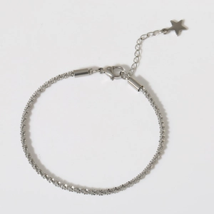 Macro shot of silver shimmer chain bracelet with lobster clasp and star charm pendant