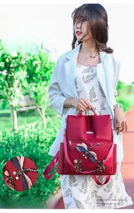 Detail of red oxford backpack featuring intricate dragonfly embroidery and gemstone accents