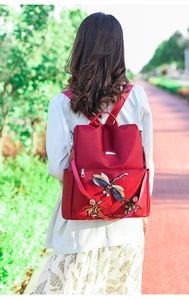 Close-up of red waterproof oxford backpack featuring intricate dragonfly embroidery details