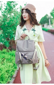 Detail of floral and dragonfly embroidery on purple waterproof oxford nylon backpack