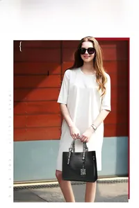 Sac cabas noir à motif crocodile avec anses en serpent porté par un mannequin en robe blanche