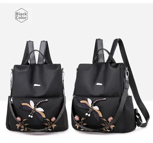 Detail of dragonfly and floral embroidery on a black waterproof Oxford backpack
