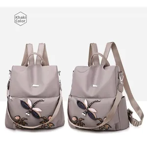 Detail view of khaki waterproof oxford backpack featuring vintage dragonfly embroidery