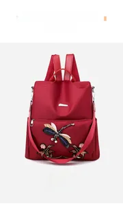 Detail of dark red oxford backpack featuring dragonfly and floral embroidery with beads
