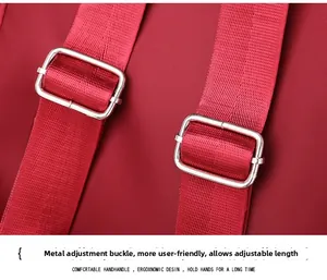 Detail of red oxford backpack straps with adjustable silver metal buckles and reinforced stitching