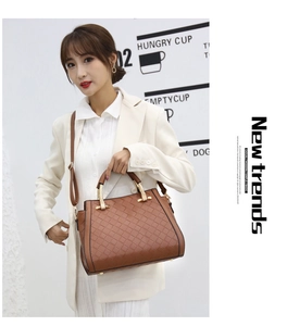 Dettaglio borsa in pelle intrecciata marrone con manici dorati su modella in abito bianco