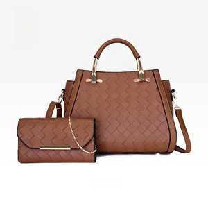 Set borsa tote e bustina intrecciate marroni con finiture dorate su sfondo bianco