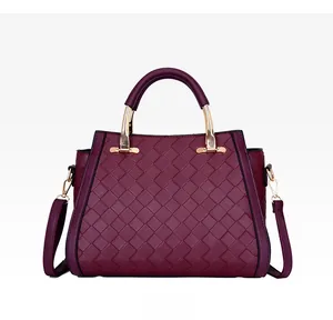 Dettaglio della borsa tote intrecciata bordeaux con fibbie dorate e manico rigido