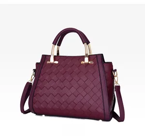 Dettaglio della trama in pelle intrecciata e del manico in metallo dorato della borsa bordeaux