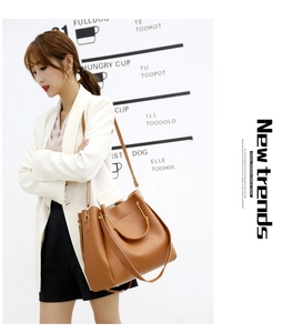 Detail of tan leather tote bag showing adjustable shoulder strap and double handles