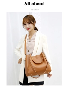 Brown leather tote bag with gold metal ring handles and adjustable shoulder strap on model