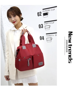 Detailed view of large red nylon tote bag featuring durable gray straps and silver zippers