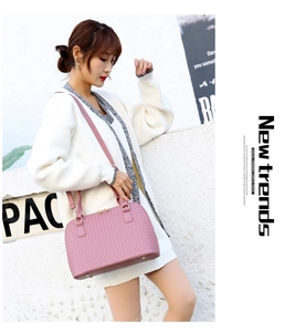 Pink woven PU leather shell bag with double handles and shoulder strap worn by model