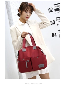 Detail of red nylon tote bag with multi-pocket design and adjustable silver handles