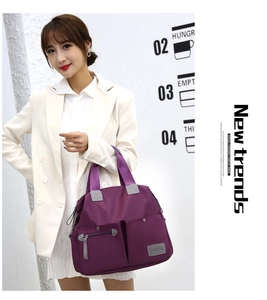 Close-up of a large purple nylon tote bag with multiple zip pockets on a stylish model