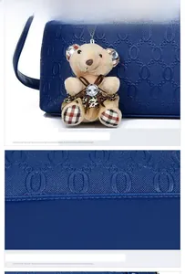 Detail der dunkelblauen Handtasche mit Buchstabenprägung und Plüsch-Teddybär-Anhänger