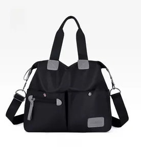 Detailed front view of black nylon handbag with functional zip pockets and wide strap