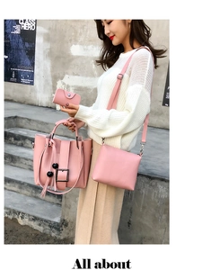 Dreiteiliges rosa Lederhandtaschen-Set mit Quastenanhänger vor grauem Hintergrund