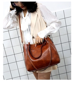 Bolso tote marrón vintage de piel sintética brillante usado por una modelo