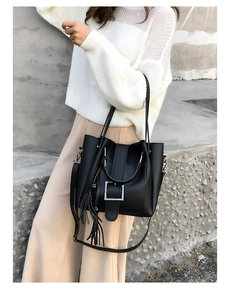 Detail einer schwarzen Leder-Beuteltasche mit silberner Schnalle und Fransenanhänger
