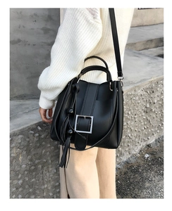 Detail der schwarzen Beuteltasche mit Silberschnalle und elegantem Quastenanhänger am Model