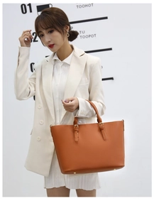 Detail of caramel leather tote bag with sturdy buckle handles and bottom protective studs