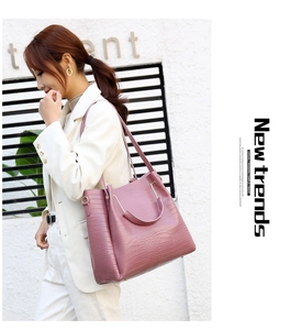 Detail of pink croc-embossed tote bag featuring a metallic handle and side texture