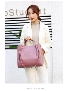 Close-up of pink embossed faux leather handbag with elegant gold ring handles and texture