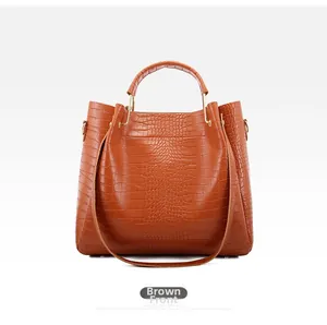 Detailed front view of brown crocodile texture handbag with gold hardware and strap