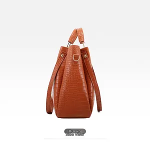 Side view of brown crocodile-effect bucket bag with golden D-ring hardware details