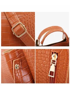 Detail of adjustable strap buckle and gold zipper on brown embossed crocodile handbag