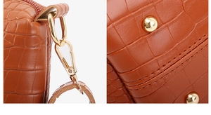 Detailed macro view of crocodile embossed leather bag with gold hooks and protective feet