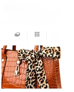 Detail of orange crocodile embossed handbag with leopard print bow and metal padlock