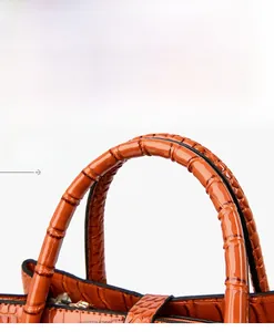 Detailed macro view of orange crocodile-embossed leather handle and high-quality stitching