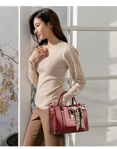 Close-up of wine red crocodile embossed handbag with leopard print silk scarf handle
