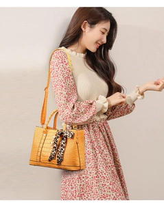 Detail of yellow crocodile pattern handbag with leopard print silk scarf and long shoulder strap