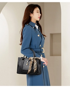Detail of black crocodile pattern handbag with leopard print scarf on a shoulder bag strap