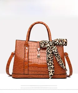 Close-up of brown crocodile texture handbag with leopard silk scarf on handle