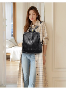 Close-up of black woven leather backpack with dual zipper details on a female model