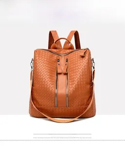 Front detail of a tan woven PU leather backpack with tassel zippers and top handle