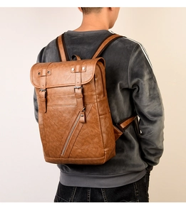 Vista posteriore di un uomo con un grande zaino vintage in pelle PU marrone con fibbie