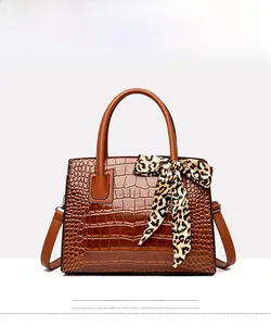 Vue détaillée du sac à main marron à motif crocodile et poignée avec foulard léopard