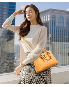 Détail de la texture motif crocodile et du fermoir métallique sur le sac à main orange