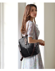 Detail view of a black faux leather backpack with brown straps worn over a floral dress