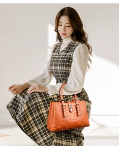 Vue détaillée de la texture crocodile orange sur un sac à main avec fermoir métallique